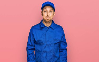 Kel, sakallı, işçi tulumu giyen, komik yüzlü, yanak şişiren adam. Havayla şişmiş ağız, çılgın bir ifade.. 