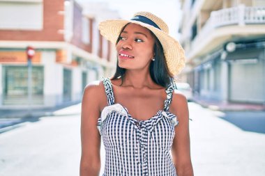Genç Afro-Amerikan kadın tatilde gülümsüyor ve şehrin sokaklarında mutlu bir şekilde yürüyor.