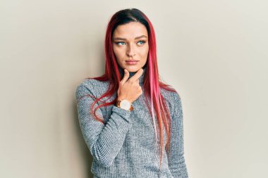 Elleri çenesinde gündelik giysiler giyen, soru soran, düşünceli bir genç beyaz kadın. Düşünceli bir yüzle gülümsüyor. şüphe kavramı. 