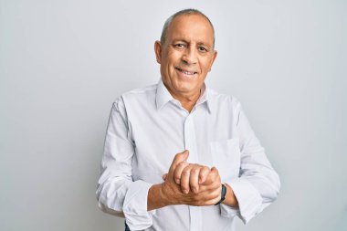 Yakışıklı, beyaz gömlekli, elleri çapraz parmaklı, rahat ve neşeli gülümseyen bir adam. Başarı ve iyimserlik 