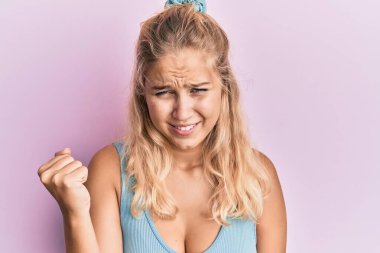 Kızgınlık ve kızgınlık içinde genç sarışın bir kız öfkeyle bağırırken yumruğunu sallıyor ve öfkeleniyor. öfke ve agresif konsept. 