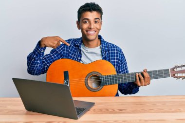 Genç, yakışıklı, Afro-Amerikalı bir adam internetten klasik gitar çalmayı öğreniyor. Parmakla göstererek mutlu ve gururlu bir kendini gösteriyor. 