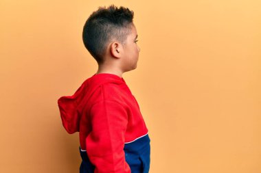 Tişörtünü giymiş İspanyol bir çocuk. Taraf arıyor, rahat bir poz veriyor. Kendine güvenen bir gülümsemesi var.. 