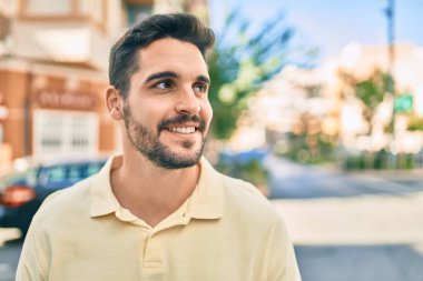 Genç İspanyol adam gülümseyerek şehirde mutlu bir şekilde yürüyor..