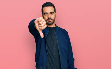 Gündelik kıyafetler giyen genç İspanyol adam mutsuz görünüyor ve reddediliyor ve olumsuz bir hareket yapıyor. kötü ifade. 