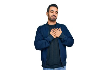 Gündelik kıyafetler giyen genç İspanyol adam elleri göğsünde, gözleri kapalı ve yüzünde minnet dolu bir jest ile gülümsüyor. sağlık kavramı. 