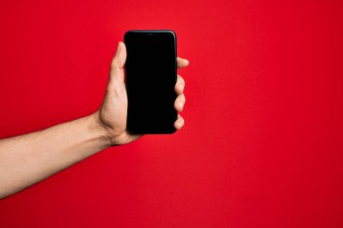 Kafkas genci elinde akıllı telefon var. İzole edilmiş kırmızı arkaplanda ekranı gösteriyor.