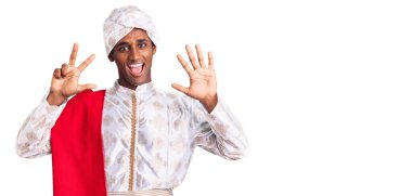 Gelenek giyinmiş Afrikalı yakışıklı bir adam Sherwani sari elbisesi giyiyor. Sekiz numaralı parmaklarıyla işaret ediyor. Kendinden emin ve mutlu gülümsüyor.. 