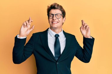 İş elbisesi giyen ve kravat takan yakışıklı beyaz adam umut ve gözleri kapalı bir şekilde gülümseyerek el sallıyor. Şans ve batıl inançlar. 