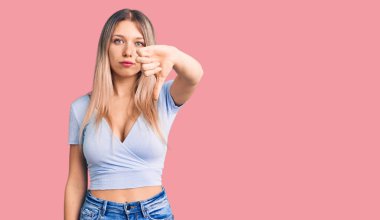 Genç, güzel, sarışın, sıradan kıyafetler giyen mutsuz görünen, reddedilmiş ve olumsuz davranışlar sergileyen bir kadın. kötü ifade. 