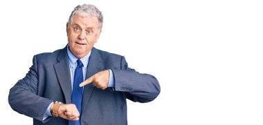 Kıdemli gri saçlı adam iş ceketi giyiyor. Aceleyle saati, sabırsızlığı, son teslim tarihini geciktirdiği için kızgın ve sinirli olduğunu gösteriyor. 