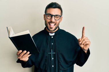 Genç İspanyol rahip elinde İncil 'le elini uzatıp dilini uzatıyor. Komik bir ifadeyle mutlu.. 