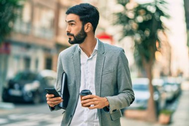 Zeki telefon kullanan ve şehirde kahve içen Latin asıllı genç bir işadamı..