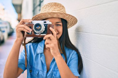 Tatildeki genç Latin turist kız şehirde klasik kamera kullanarak mutlu mesut gülümsüyor..