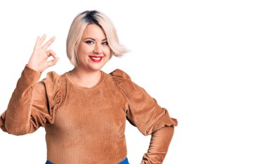 Genç sarışın, iri yarı, sıradan bir kazak giyen, gülümseyen, el ve parmaklarıyla 