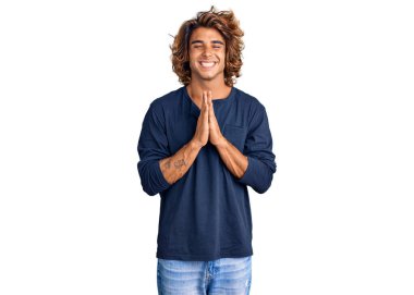 Gündelik giysiler giyen genç İspanyol adam elleri bağlı yalvarıyor ve dua ediyor. Yüzünde umut ifadesi var. Çok duygusal ve endişeli. Yalvarıyor. 