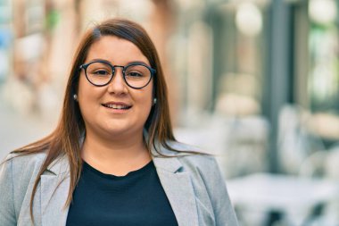 Latin kökenli genç ve iri yarı bir iş kadını şehirde mutlu mesut dikiliyor..