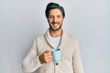 Genç İspanyol bir adam bir fincan kahve içiyor. Olumlu ve mutlu görünüyor. Kendine güvenen bir gülümsemeyle dişlerini gösteriyor. 