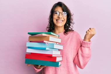 Genç İspanyol kadın elinde kitaplarla gururla bağırıyor zaferi ve başarıyı kutluyor. 