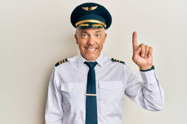 Yakışıklı, olgun, uçak pilotu üniforması giyen bir numaralı parmağını gösterip, gülümseyerek kendinden emin ve mutlu.. 