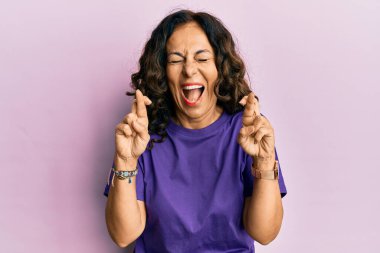 Orta yaşlı İspanyol kadın parmaklarını çapraz yapıp gülüyor ve kahkahalarla gülüyor.. 