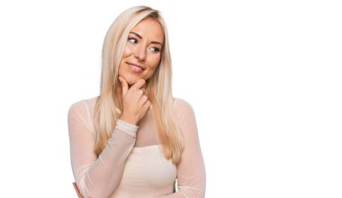 Elleri çenesinde gündelik giysiler giymiş soru soran genç sarışın kadın, düşünceli bir ifade. Düşünceli bir yüzle gülümsüyor. şüphe kavramı. 