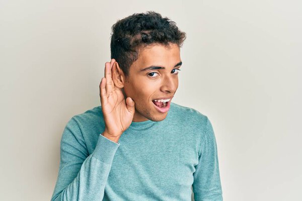 Young handsome african american man wearing casual clothes smiling with hand over ear listening and hearing to rumor or gossip. deafness concept.