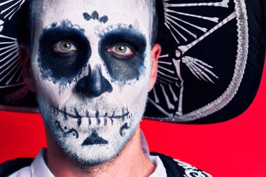 Meksika 'daki geleneksel ritüellerden giyinmiş korkunç bir adamın kırmızı arka plan üzerinde makyaj ve kıyafet giydiği gün.