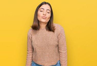 Genç ve güzel bir kadın, günlük kıyafetler giyip kameraya bakıyor ve güzel ve seksi bir şekilde havadan öpücük yolluyor. aşk ifadesi. 