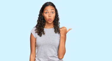 Gündelik giysiler giyen Afro-Amerikan genç kız elleri yana doğru işaret ederek şaşırdı, ağzı açık hayret içinde kaldı.. 