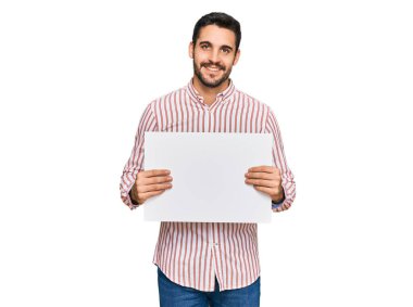 Genç İspanyol adam boş pankart tutuyor. Olumlu ve mutlu görünüyor. Kendine güvenen bir gülümsemeyle dişlerini gösteriyor. 