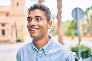 Genç Latin adam gülümseyerek şehirde mutlu mesut yürüyor..