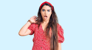 Esmer genç kız şok olmuş gibi giyinmiş, şüpheci ve alaycı görünüyor, ağzı açık kalınca şaşırıyor. 