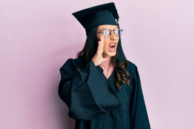 Mezuniyet şapkası ve tören cübbesi takan genç İspanyol kadın el ve ağızla bağırarak ve yüksek sesle bağırıyor. iletişim konsepti. 