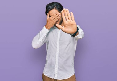 İş gömleği giyen ve gözlük takan genç İspanyol adam elleriyle gözlerini kapatıyor ve üzgün ve korku ifadeleriyle jestleri durduruyor. utangaç ve olumsuz kavram. 