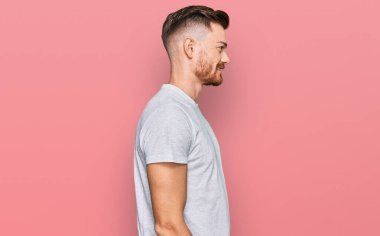 Gri tişört giyen genç, rahat bir görünüm takınan, rahat yüzlü, kendine güvenen bir gülümseme takınan kızıl saçlı adam.. 