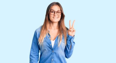 Yüzünde mutlu ve havalı bir gülümseme olan günlük kıyafetler ve gözlük takan güzel beyaz bir kadın. şanslı kişi. 