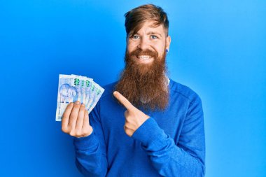 Genç İrlandalı kızıl saçlı adam Güney Afrika 'yı tutuyor. 100 rand' lık banknotlar, mutlu bir şekilde el ve parmağıyla işaret ediyor. 