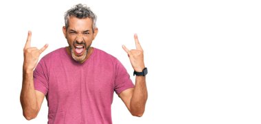 Orta yaşlı, gri saçlı, günlük kıyafetler giyen çılgın bir ifadeyle bağıran elleri havada rock sembolü yapan bir adam. Müzik yıldızı. ağır müzik konsepti. 