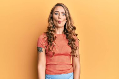 Gündelik kıyafetler giyen genç sarışın kız dudaklarıyla balık suratı yapıyor, çılgınca ve komik bir jest. Komik ifade. 