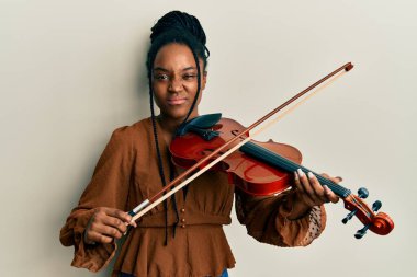 Saçları örgülü, keman çalan, kuşkucu ve gergin Afro-Amerikalı bir kadın sorun yüzünden kaşlarını çatıyor. negatif kişi. 