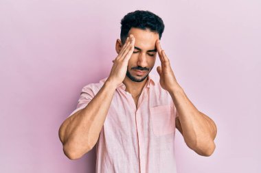 İspanyol asıllı genç adam gündelik giysiler giyiyor. Baş ağrısı çekiyor. Acı ve migren yüzünden çaresiz ve stresli. Eller başının üstünde.. 