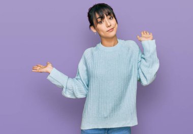 Gündelik kıyafetler giyen, elleri ve kolları havada, kafası karışmış genç İspanyol kadın. şüphe kavramı. 