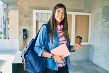 Genç İspanyol öğrenci gülümseyerek kitabı tutuyor ve üniversitede kahve içiyor..