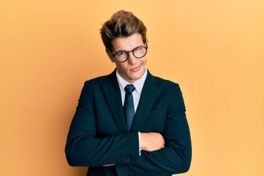 İş elbisesi giyen yakışıklı beyaz adam kuşkucu ve gergin kravat takıyor. Yüzünde çapraz kollarla onaylamayan ifade var. negatif kişi. 