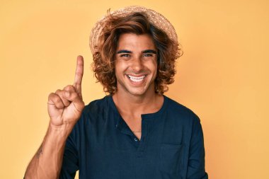 Yaz şapkası takan genç İspanyol bir numarayı gösterip işaret ederken kendinden emin ve mutlu bir şekilde gülümsüyor.. 