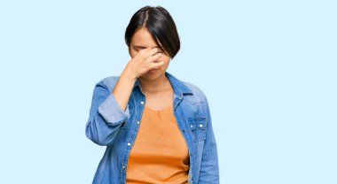 Kısa saçlı, sıradan bir kot ceket giyen, burnu ve gözleri ovuşturup yorgun ve başı ağrıyan genç ve güzel İspanyol bir kadın. Stres ve hüsran kavramı. 