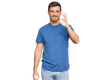 Sıradan kıyafetler giyen yakışıklı beyaz adam gülümsüyor. El ve parmaklarıyla tamam işareti yapıyor. başarılı ifade. 