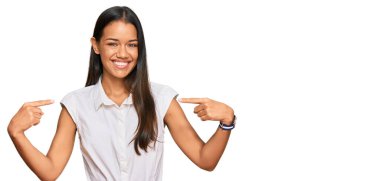 Güzel İspanyol kadın gündelik kıyafetler giyiyor. Kendine güveniyor gibi görünüyor. Yüzünde gülücükler, kendini gururlu ve mutlu olarak gösteriyor.. 