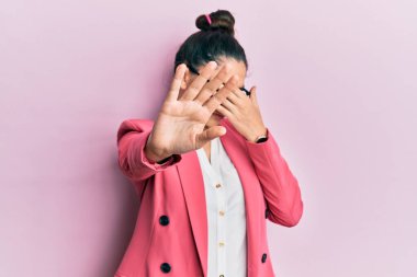 Güzel bir ortadoğulu kadın iş ceketi giyiyor ve gözlük takıyor. Gözlerini elleriyle kapatıyor ve üzgün ve korku ifadeleriyle jest yapıyor. utangaç ve olumsuz kavram. 